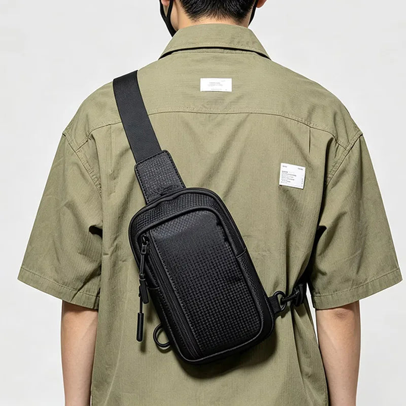 Eine Person trägt eine schwarze, vielseitige Unisex-Crossbody-Tasche über der Brust auf dem Rücken.