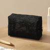 Black lace mesh makeup bag resting on a wooden surface with a gold applicator nearby.