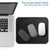 A black mouse pad with a stitched edge is shown next to a laptop, demonstrating its non-slip surface.