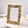 An elegant golden ginkgo leaf resin photo frame displayed on a white table.