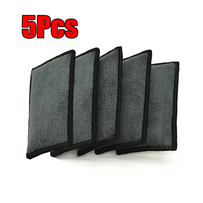 Five black microfiber scrubbing sponges stacked together.