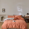 A soft peach quilted duvet cover set displayed on a bed with light wood flooring and a neutral wall.