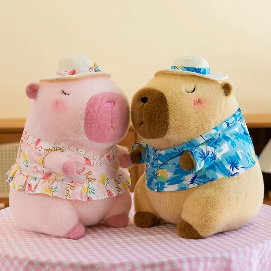 A pink capybara plush toy wearing a floral dress and a yellow duck swim ring, sitting on a pink surface.