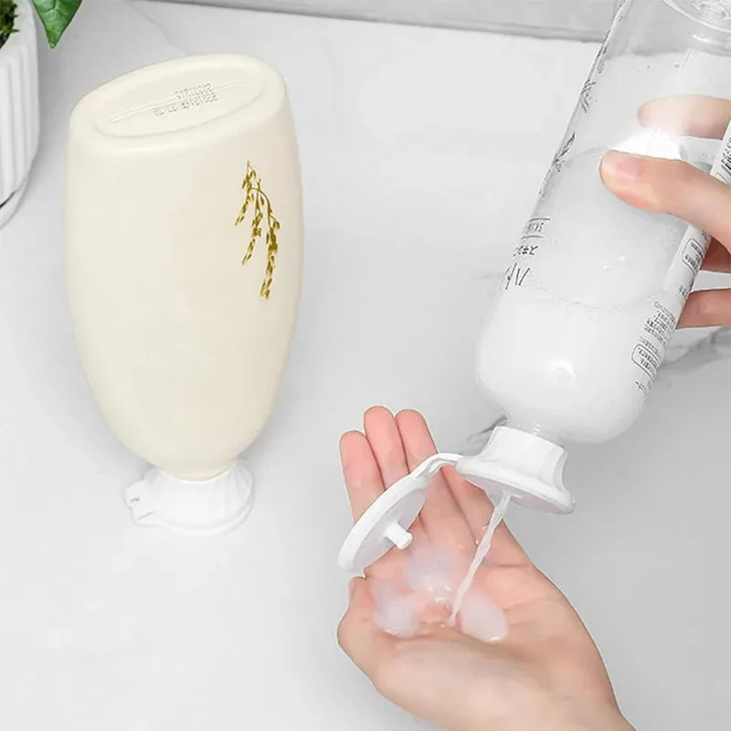 Eine Hand gießt weiliche Flüssigkeit aus einem umgedrehten Flaschenverschluss in ein Glas, neben dem leeren Verschluss.