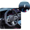 Close-up view of a black steering wheel with white accents and a leather cover on a car dashboard.