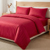 A set of satin striped jacquard duvet covers in deep red with a light wood bed frame and neutral bedding.