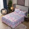 Un lit avec une jupe de lit à motifs floraux violets et roses et une tête de lit sombre.
