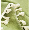 Close-up of a sage green farmhouse tablecloth featuring white cotton tassels along the edge.