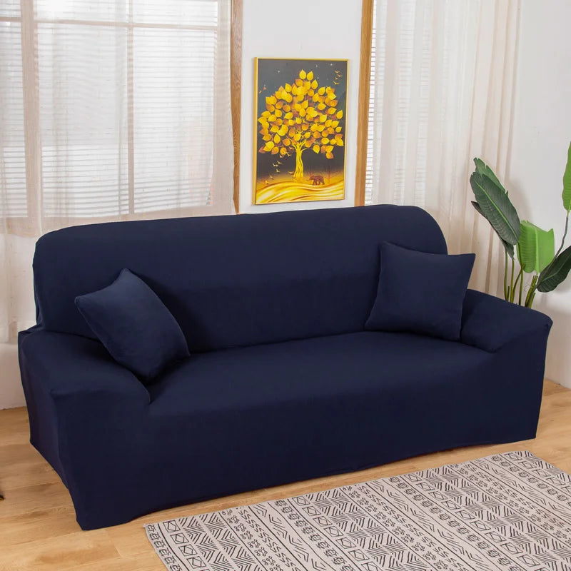 A navy blue silky soft stretchable sofa cover displayed on a couch in a bright room.