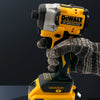 A hand is holding a yellow and black DEWALT 20V brushless cordless impact driver tool.