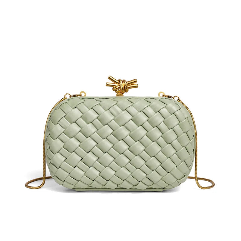 A light sage green handwoven clutch bag with a woven texture and a gold-toned chain strap.