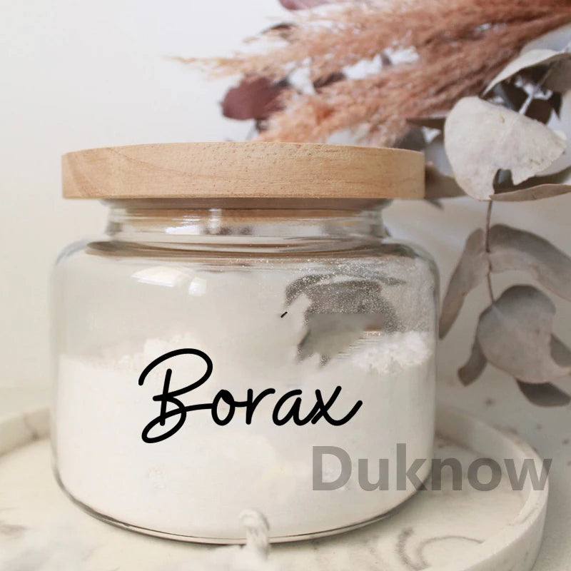 A clear jar filled with white Borax powder, set against a blurred background of dried foliage.