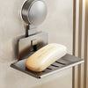 A silver wall-mounted soap dish with a suction cup dispenser is installed on a beige wall.