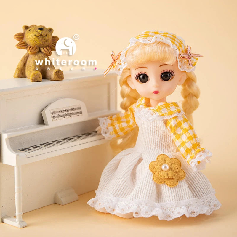 A blonde fashion doll with long hair and a yellow checkered dress stands next to a white piano and a stuffed lion.