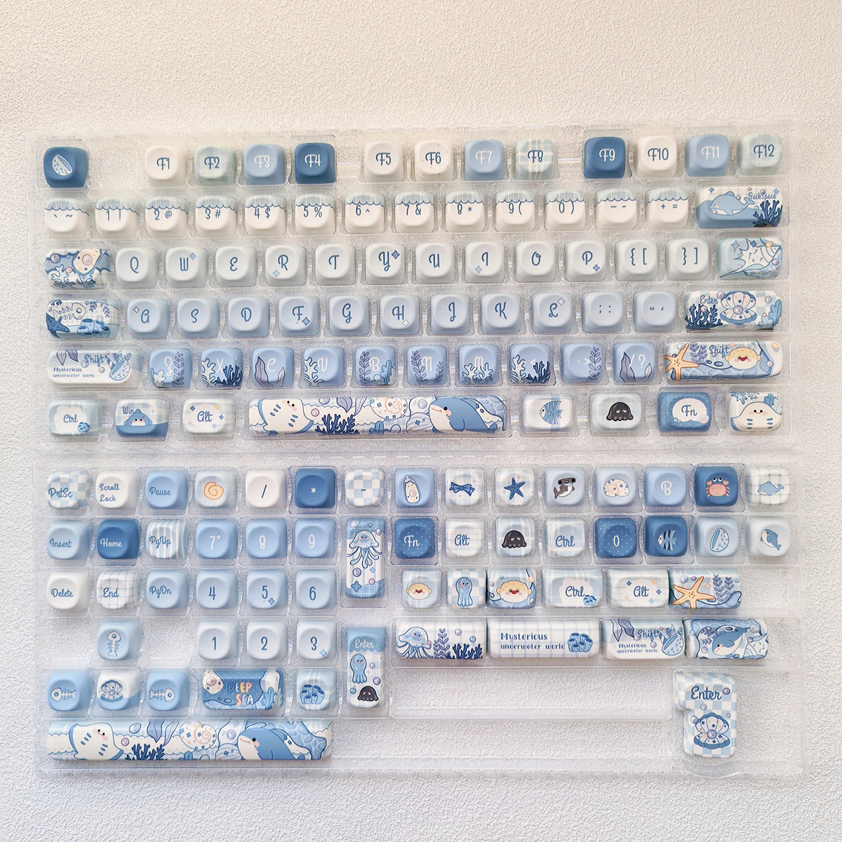 A collection of ocean blue PBT keycaps for mechanical keyboards arranged in a plastic tray.