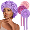 A woman models a purple satin sleeping bonnet with an adjustable tie and matching pink satin ear ties.