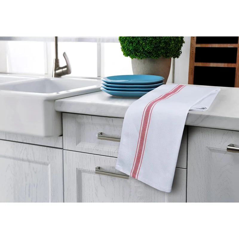 White kitchen towels with red stripes are displayed on a countertop next to a sink and blue plates.
