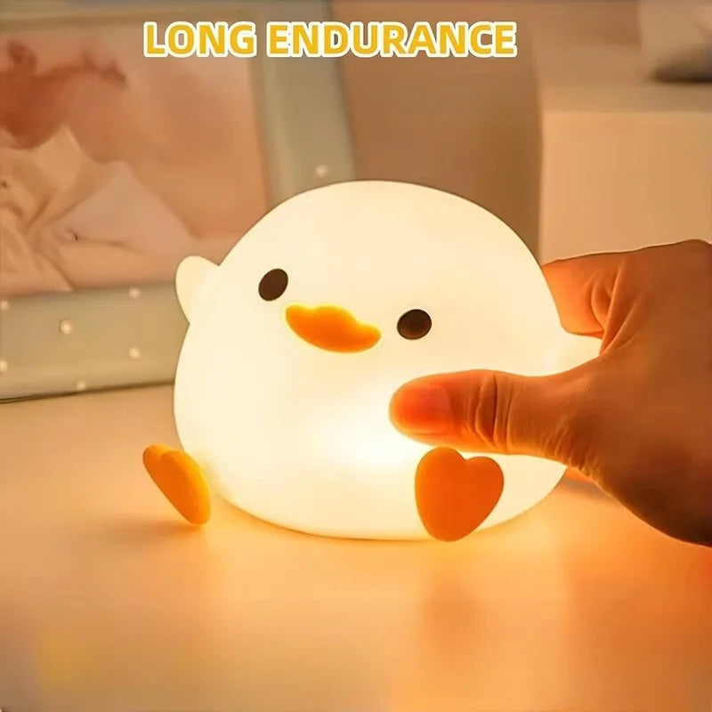 A hand is touching a glowing white duck night light, demonstrating its long endurance.