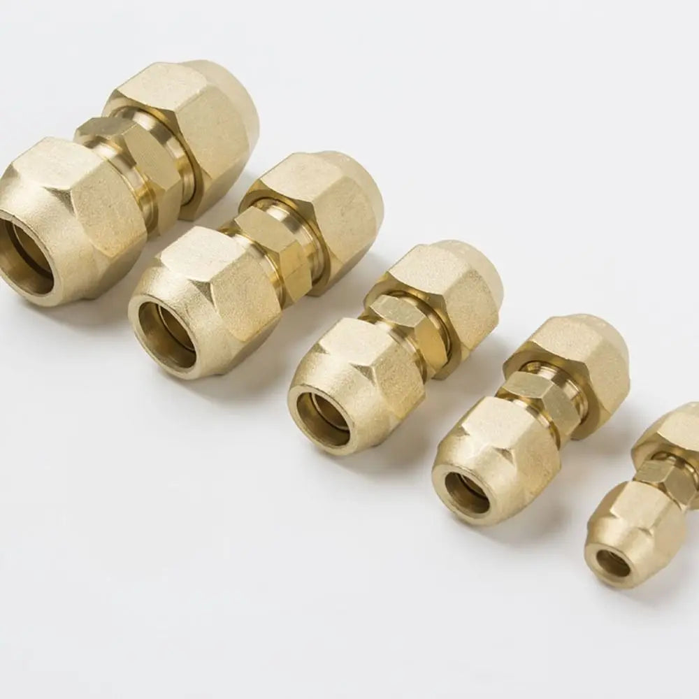 A collection of brass copper pipe extension fittings with flare nuts arranged diagonally on a white background.