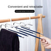 A close-up of a retractable stainless steel pants hanger with multiple layers being used on a wooden rack.