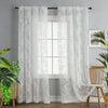 A pair of sheer white floral lace curtains hanging in a window with a white frame and light gray wall.