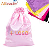 Pinker Satin-Aufbewahrungstasche mit Logo und mehrere bunte Stofftaschen daneben.