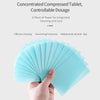 A hand holds a fan of light blue concentrated compressed tablets for integrated cleaning and care.