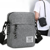 A gray mini crossbody phone bag with a black adjustable strap is shown next to a person wearing a white shirt.