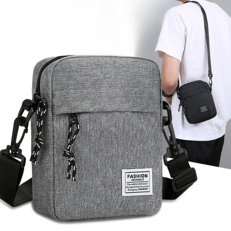 A gray mini crossbody phone bag with a black adjustable strap is shown next to a person wearing a white shirt.