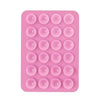 A pink silicone suction cup phone holder mat with multiple circular indentations.