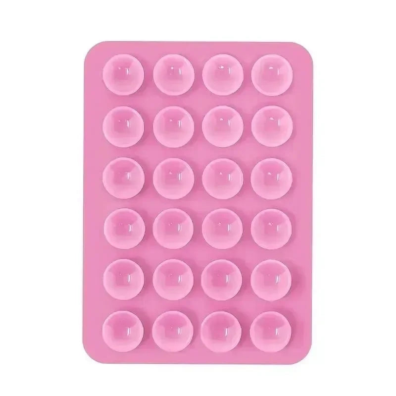A pink silicone suction cup phone holder mat with multiple circular indentations.