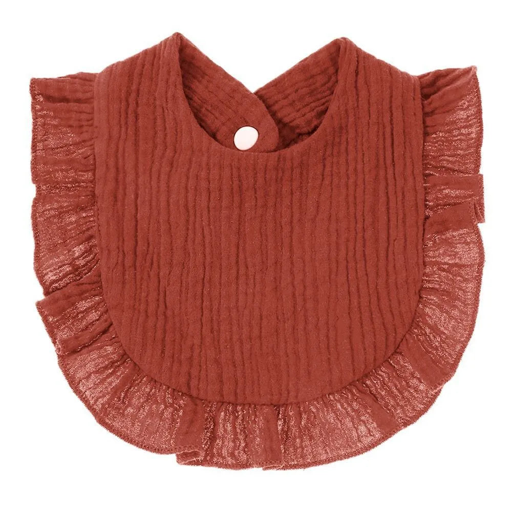 A rust-colored, ribbed cotton baby bib in a bandana style with ruffled edges.