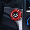 A close-up of a red rotating protective cover for a car ignition start button on a dark panel.