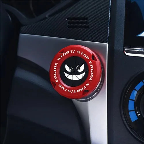 A close-up of a red rotating protective cover for a car ignition start button on a dark panel.