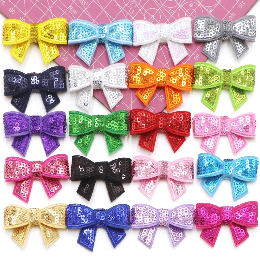 A collection of five colorful sequin bow patches in various colors and patterns for DIY crafts.