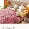 A pink quilted blanket is displayed on a beige sofa next to a window with natural light.