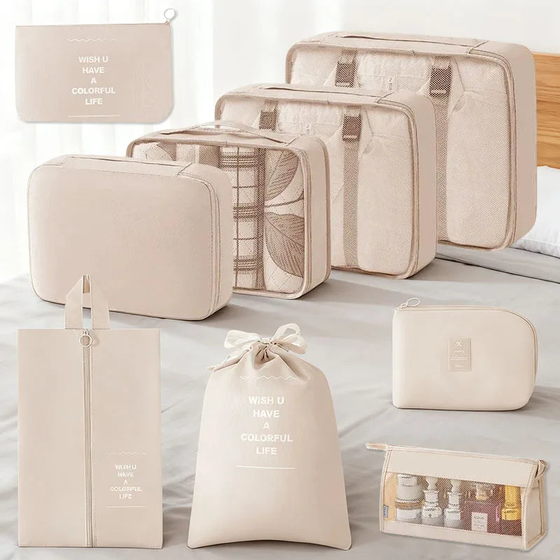 A set of beige travel packing cubes and storage organizer bags displayed on a light gray surface.