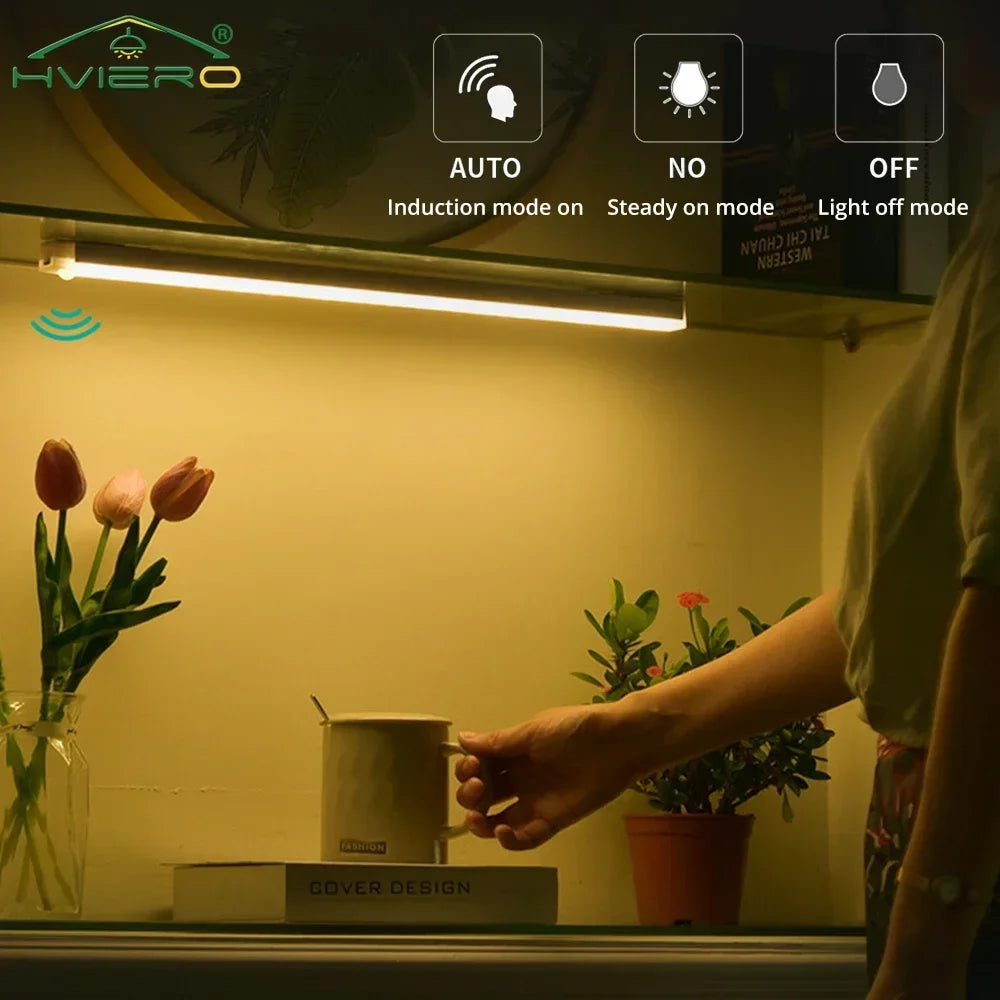 A close-up of a white LED light fixture mounted above a shelf, illuminating a room with plants and a mug.