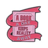 Enamel pin featuring text that reads A BOOK A DAY KEEPS REALITY AWAY on a pink background with a red ribbon border