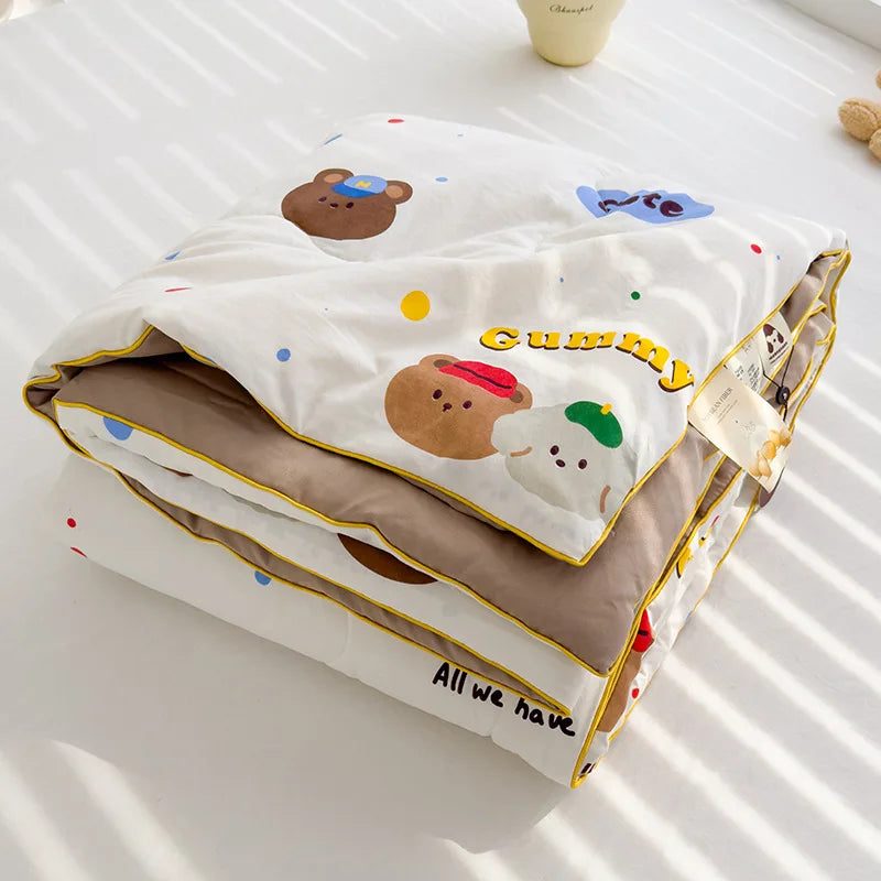 A light-colored quilt featuring cute brown and white bear designs with the text Gummy All we have.