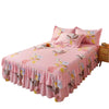 Jupe de lit à motifs floraux roses avec ourlet froncé et oreillers assortis sur un lit.