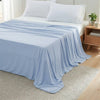 Light blue ice silk blanket draped over a bed and spread on a rug.