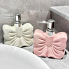 A pink ceramic pump dispenser with a silver pump mechanism sits on a gray countertop next to a white sink.