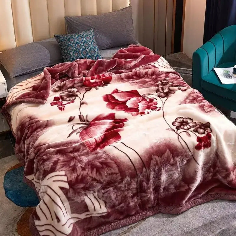 Plüschdecke mit rotem Rosenmuster in tiefen Weinrot- und Rosatönen, drapiert auf einem Sofa.