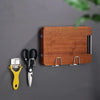 A wooden block holds a pair of scissors and a yellow suction cup tool against a gray background.