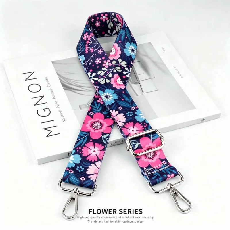 A floral patterned fabric strap in purple and pink is displayed on a white box.