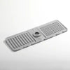A gray silicone faucet draining mat with raised ridges and a central drain hole.