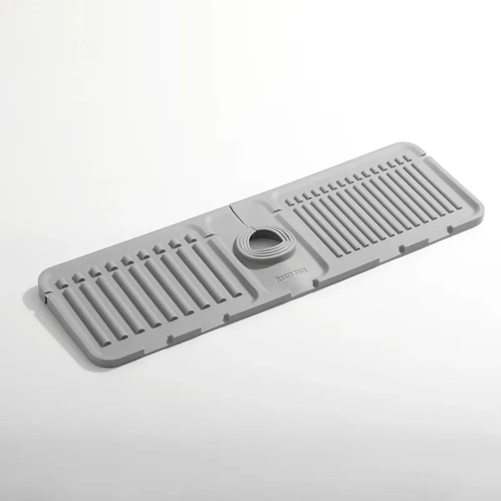 A gray silicone faucet draining mat with raised ridges and a central drain hole.