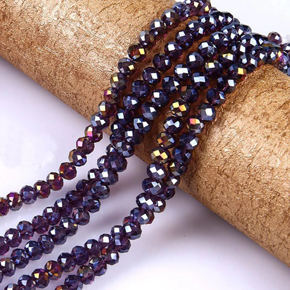 Purple faceted crystal glass spacer beads threaded onto a golden ribbon roll