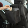 A hand places a tissue into the organizer pocket of a black foldable car trash can and organizer.